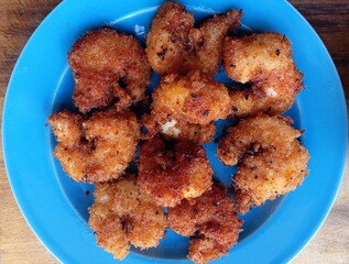 Breaded Crispy golden fried shrimp (prawns) on a blue plate. Breaded fired prawns (shrimp), a delicious seafood appetizer with golden crunchy coating and succulent juicy interior, perfect for any meal