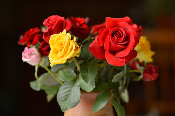 bouquet of colorful roses in the clay vintage vase at the table