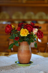bouquet of colorful roses in the clay vintage vase at the table