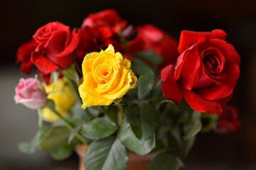 bouquet of colorful roses in the clay vintage vase at the table