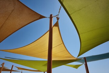 Colorful triangular sunshades against a clear blue sky
