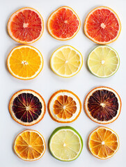 Fototapeta premium Top view of assorted dried citrus fruit slices including grapefruit, lemon, lime, and orange arranged in a grid pattern isolated on white background