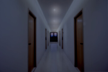Long hotel corridor with wooden doors on both sides, soft ceiling lights, and a dark nighttime ambiance leading to a window