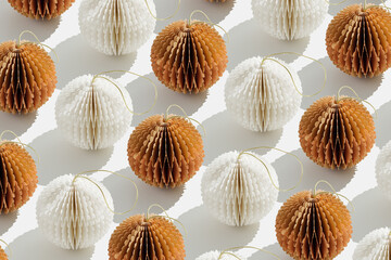 Top view of white beige honeycomb paper Christmas ornaments in minimal trend pattern on light background. New Year round balls with sun shadows, graphic layout modern holiday design, neutral color