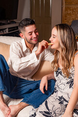 Brother gently feeding pregnant sister in warm Colombian home setting.