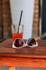Close-up of a glass with a delicious cool cocktail on a table by the pool, sunglasses are lying...