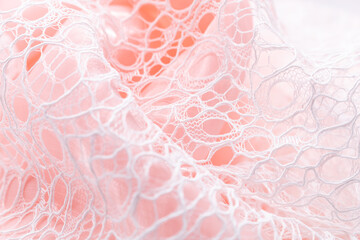 Elegant white lace fabric draped over soft pink background, showcasing intricate patterns and...