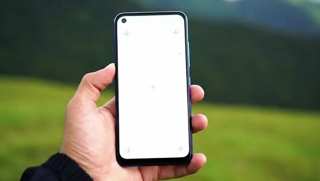 Hand holding phone with blank white screen outdoors against blurred nature view