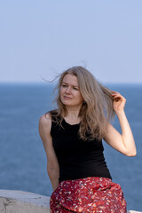 Photo of a gorgeous young woman against the backdrop of the sea on a sunny summer day