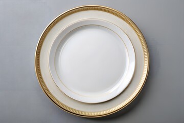 Photo of overhead shot of an empty white and gold decorative plate on gray surface
