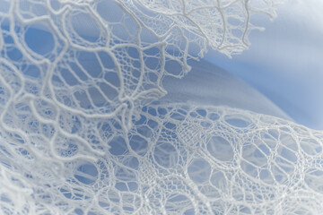Delicate white lace close-up on soft blue background, evoking elegance and romance, ideal for wedding themes, luxury fashion, feminine beauty, and textile design with chiffon, satin, and silk