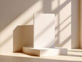 Fototapeta premium Blank book on light beige podium, sunlit room