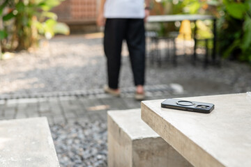 A man in a white shirt is walking past a table with a cell phone on it. The phone is an iPhone