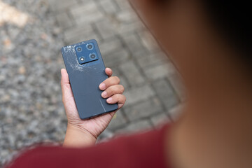 A person is holding a cell phone in their hand. The phone is laying on the grass. The grass is green and the person is standing on it