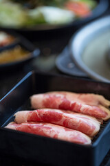 close-up of strips of raw beef arranged in a black container at korean hotpot restaurant red meat