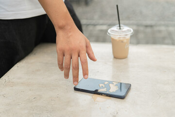 A person is wiping a cell phone with a cloth. The phone is wet and has a white substance on it