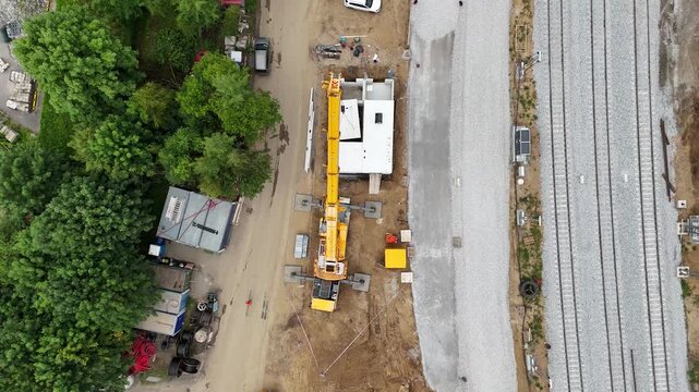 Drone aerial view of a giant construction crane lifting massive concrete structures at a mega building site, symbolizing strength, engineering progress, and the scale of modern industry.