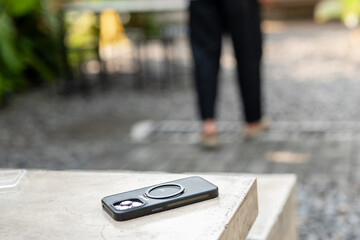 A man in a white shirt is walking past a table with a cell phone on it. The phone is an iPhone