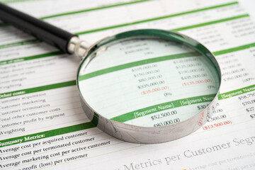Magnifying glass on spreadsheet and graph paper.