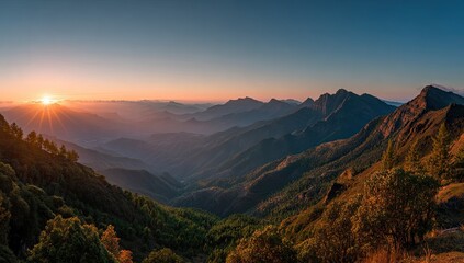 Panoramic sunset view over a vast mountain range, layers of hazy hills fading into a clear sky, sun's rays casting a golden glow on the landscape