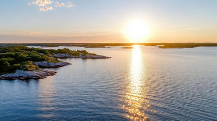 Sunset over tranquil water, reflecting light on rocky shoreline and lush greenery