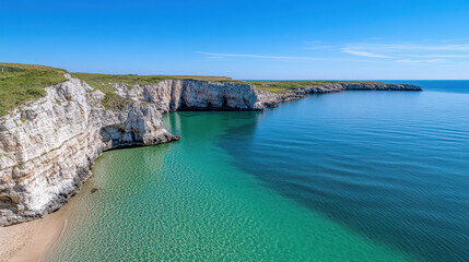 Obraz premium Coastal cliffs, clear water, serene beach, and vibrant sky create tranquil scene