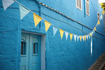Brightly colored bunting flags strung across a vibrant blue building facade