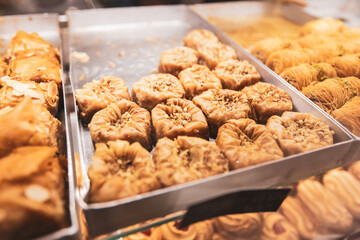 Golden traditional Middle Eastern pastries garnished with pistachios, soaked in honey syrup and...