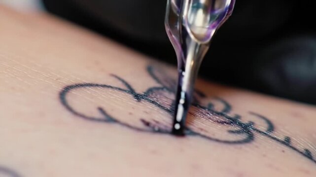 Close-up of tattoo artist's hand inking a butterfly design on an arm, showcasing the tattooing process with detail and precision.