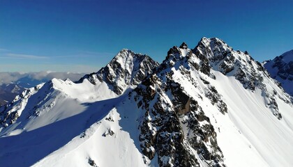 Aerial view of snow-capped mountain peaks under a clear blue sky