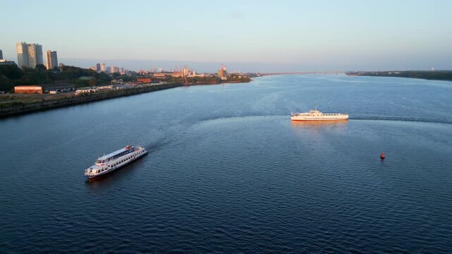 Passenger ferry navigating river at sunrise near city coastline. Clip