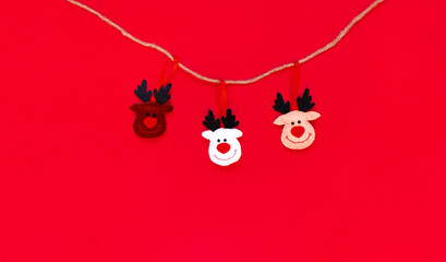 Toy Deers hanging on a rope isolated on the red background with copy space. The atmosphere of Christmas and New Year. Christmas banner, mock-up