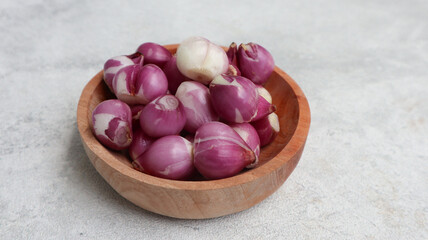 shallot onions on the wooden bowl isolated on grey background. peeled red onion