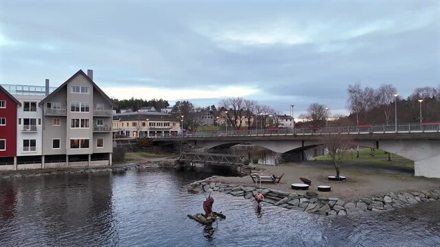 View of Steinkjer riverbank with houses bridge stone bank and swimmer diving in water 