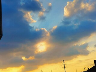  A vibrant sunset sky filled with blue and orange hues and fluffy clouds. The sun is shining...