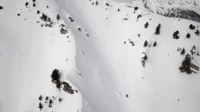 Skier descending a steep, pristine snow-covered mountain
