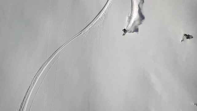 Skier descending a steep, pristine snow-covered mountain