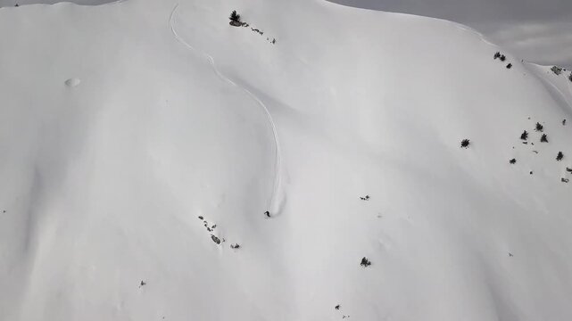 Skier descending a steep, pristine snow-covered mountain