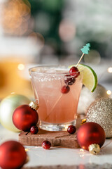 Holiday margarita with cranberry garnish, salt rim, and ornaments.