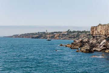 oastal cliffs with lighthouse and yacht near Cascais, Portugal