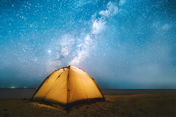 Milky Way over illuminated camping tent