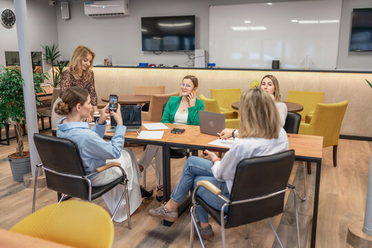 Teamwork women office: Group collaborates on laptop, phone during business meeting in modern workspace.