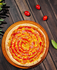Pizza topped with pepperoni and ketchup on a wooden surface in bright sunlight