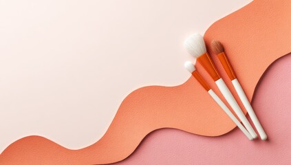 Three makeup brushes with white handles and coral-toned bristles rest on a peach and coral wavy paper background, leaving ample copy space