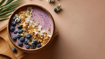 Top view of a purple smoothie bowl filled with oatmeal, blueberries and edible flowers on a beige background for a healthy breakfast.