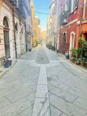 Picturesque narrow alleyways in the historic center of Cagliari, Sardinia, Italy. Colorful old buildings with balconies and flowers, cobblestone streets