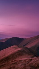 Naklejka premium Close-up grassy hills under dusky sky with pink purple hues