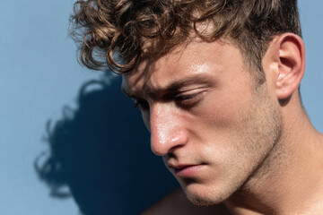 Fototapeta premium profile of man with sweaty temples displaying intense focus expression stands out against bright blue background