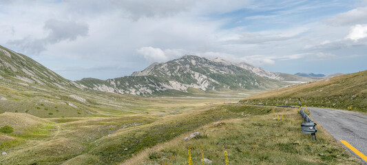 uphill winding road  on Campo Imperatore upland with Laga Mountains range in background, L'Aquila,...