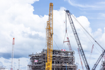 Construction site with construction crawler cranes and multi storey unfinished buildings, Many high rise cranes and industrial construction equipment, Contruction site blue sky background.